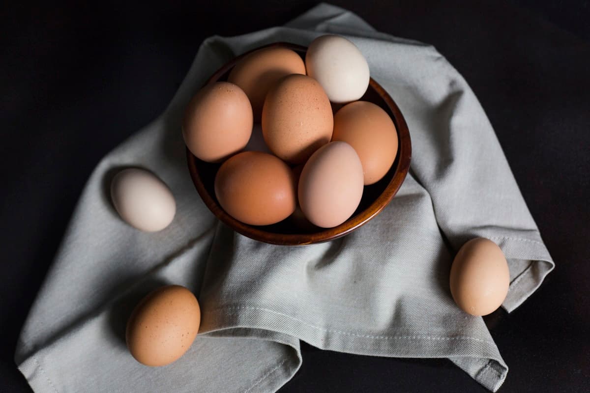 Mix of brown and cream free-range eggs nestled in a wooden bowl
